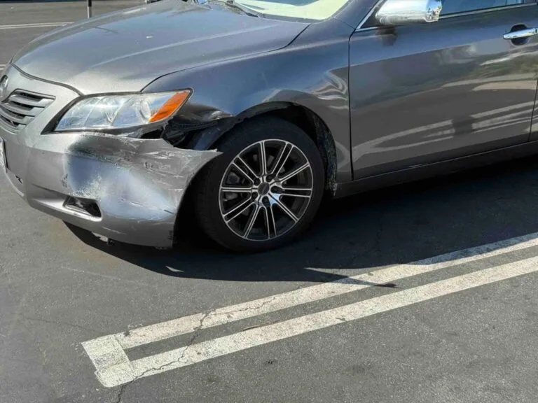 Gray damaged Toyota Camry parked near a beach in Orange County – sell my car fast with Go Car Buyer.