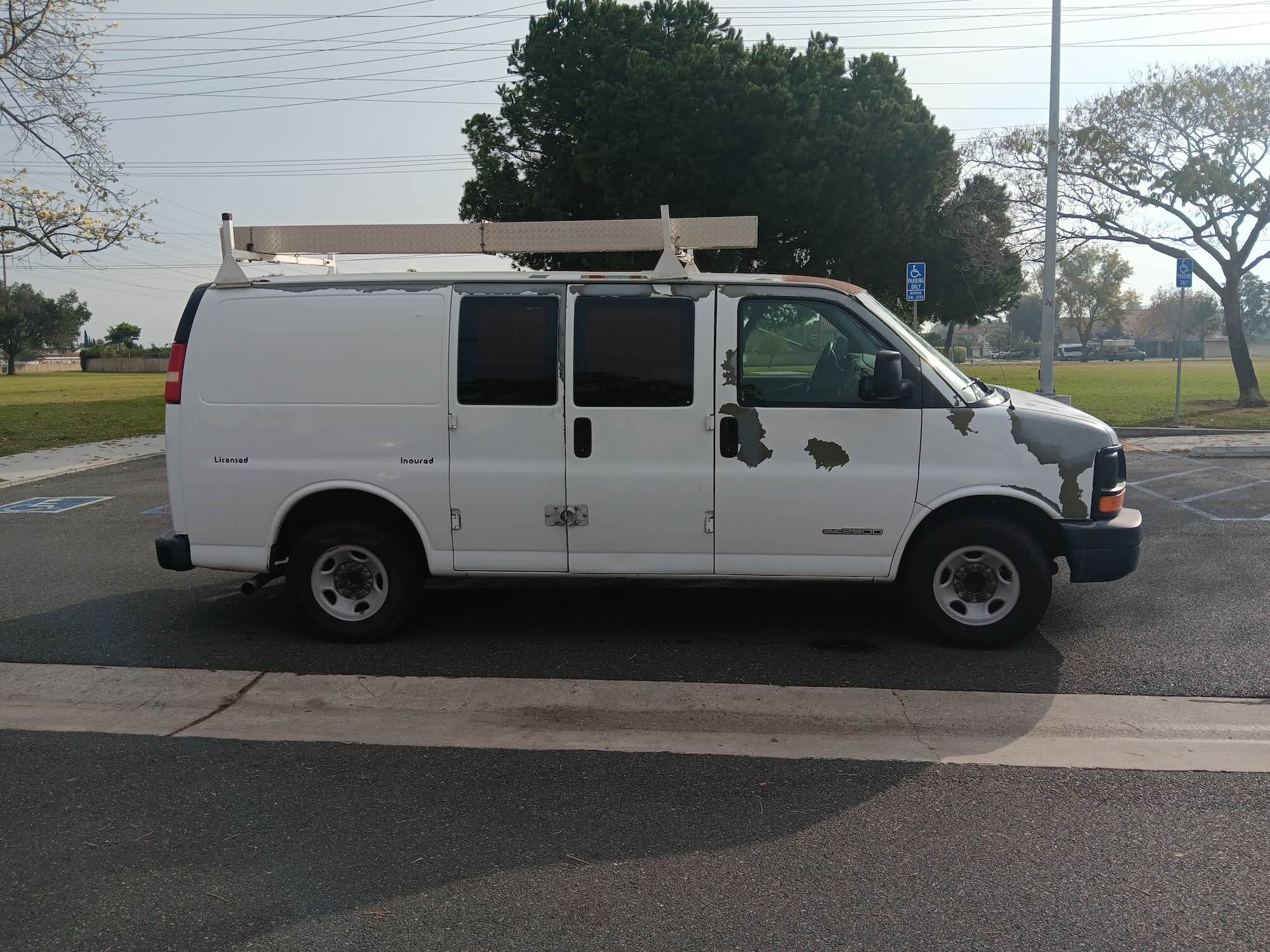 A used white Chevrolet Express cargo van with ladder rack purchased for cash by GoCarBuyer in Los Angeles, California