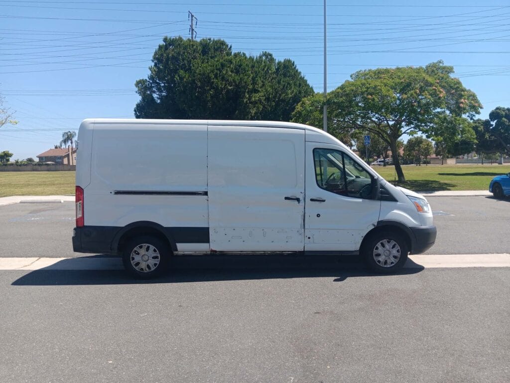 A used white Ford Transit mid-roof cargo van purchased for cash by GoCarBuyer in Los Angeles, California