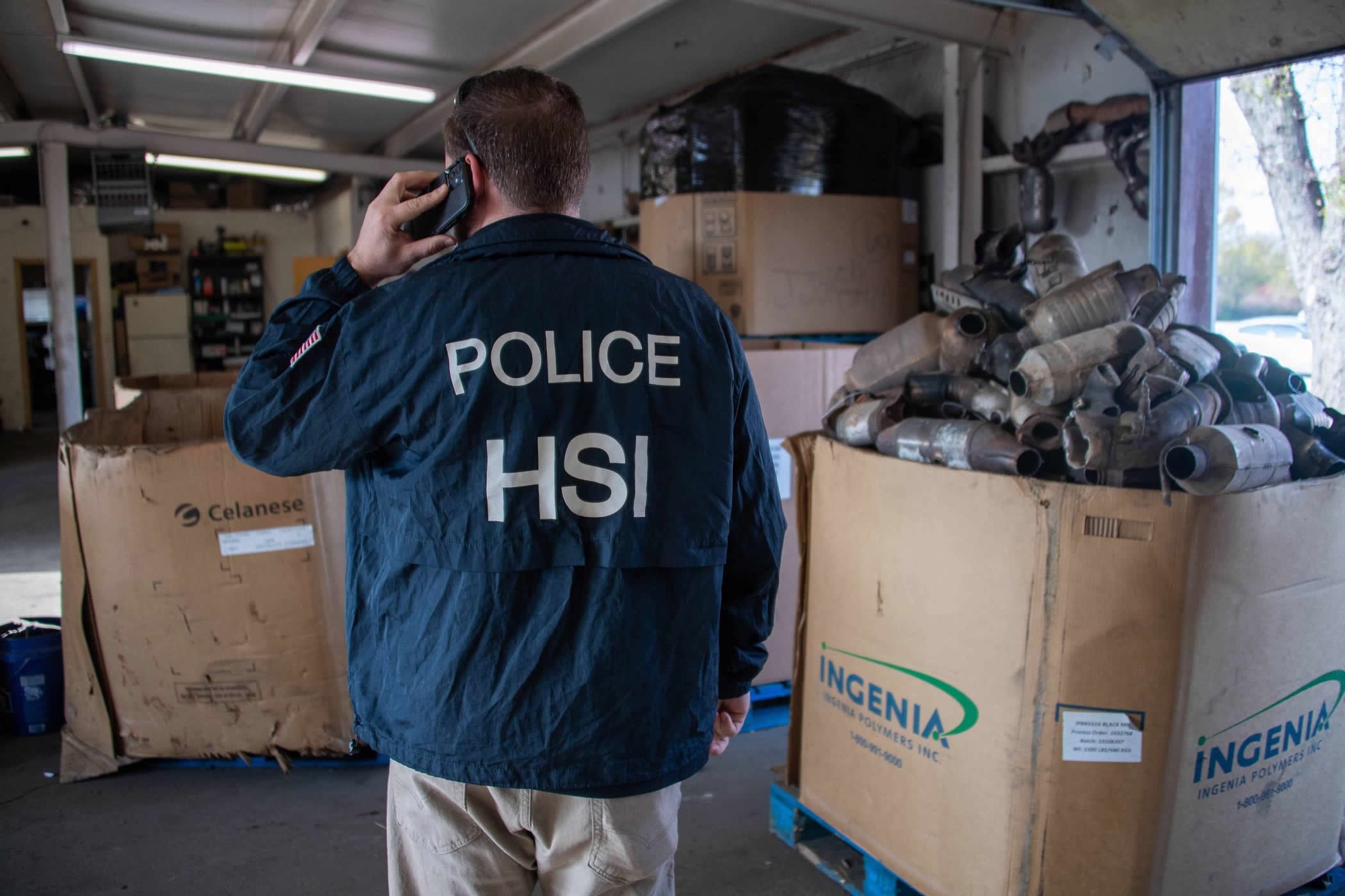 Police officer inspecting a massive pile of stolen catalytic converters. We buy cars with missing catalytic converters for cash in Southern California.