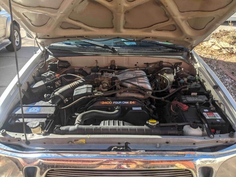 Under the hood of a first generation Toyota Tacoma showing the 3.4L V6 engine. Go Car Buyer pays cash for high mileage Toyota trucks.