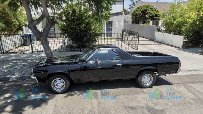 A clean, restored black classic Chevy El Camino parked in a sunny residential neighborhood in Los Angeles.