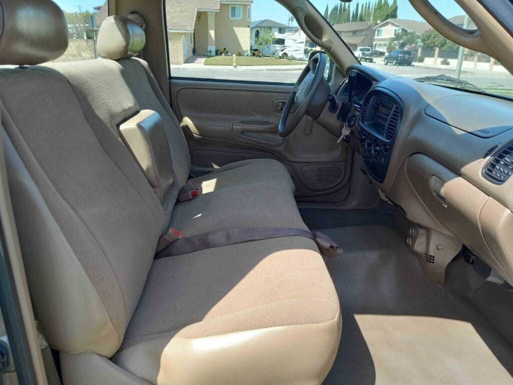 Clean tan cloth and vinyl interior of a first-generation Toyota Tundra featuring a front bench seat.