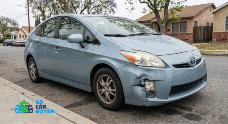 A light blue 3rd generation Toyota Prius with front bumper damage parked on a residential street in Anaheim. GoCarBuyer pays cash for damaged and high-mileage hybrids.