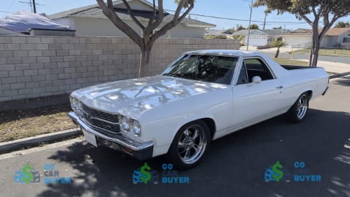 Fully restored white classic Chevy El Camino with custom chrome wheels parked in an Orange County neighborhood. Southern California classic car buyer paying top market value for numbers-matching and show-quality vintage vehicles.