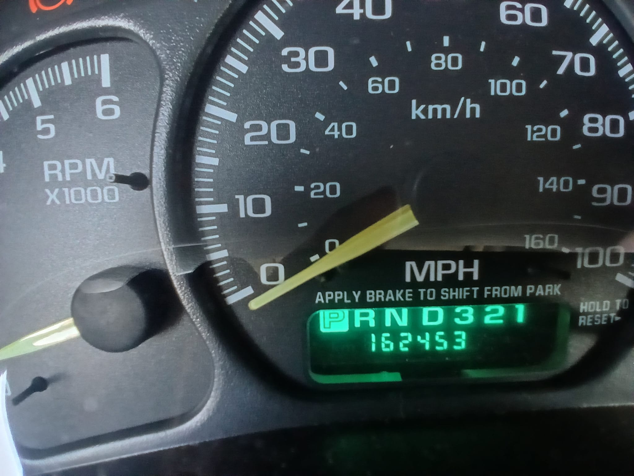 A close-up of a car dashboard with an odometer reading of 162,453 miles, representing a high-mileage vehicle.